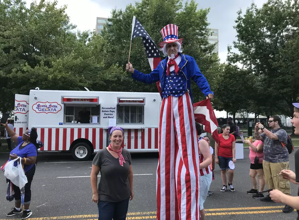 Gotta Lotta Gelata owner and uncle sam on stilts with food truck in background at a fourth of July festival