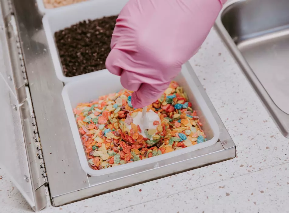 Banana pop being made with white chocolate topped with Fruity Pebbles