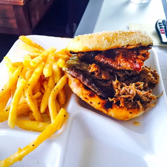 Chicharon Burger toped with Kalua pig and cheese and served on a toasted bun with crunchy fries.